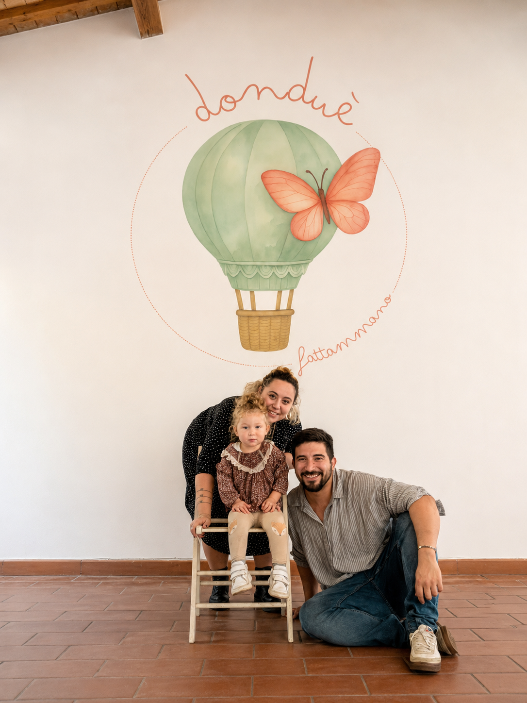 Andrea Massa con la famiglia e la piccola Vittoria davanti al logo Dondué dipinto sulla parete del laboratorio di Cecina